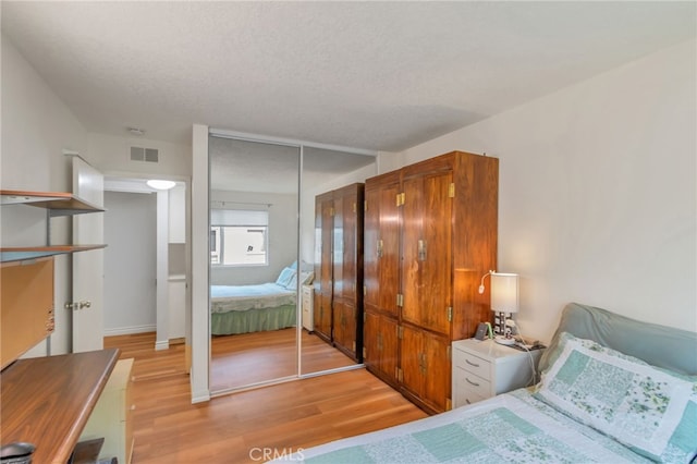 bedroom with visible vents, a textured ceiling, a closet, and light wood-style flooring