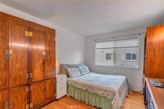 bedroom with a textured ceiling and light wood finished floors
