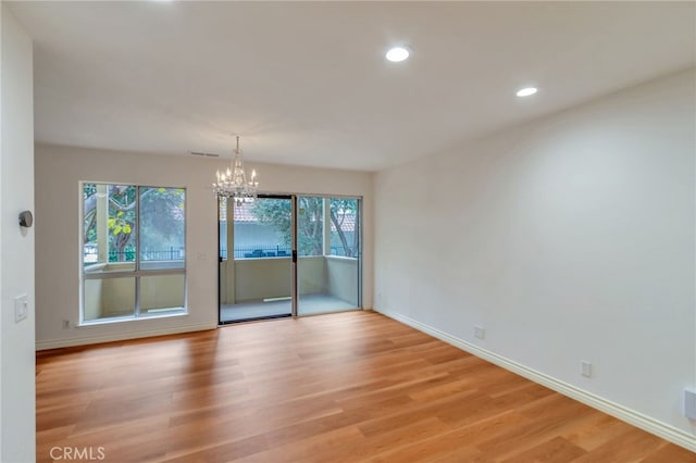 spare room with recessed lighting, a notable chandelier, baseboards, and light wood-type flooring