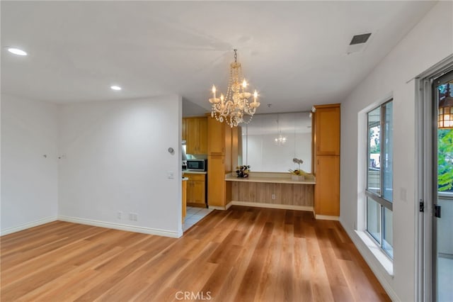 kitchen with recessed lighting, stainless steel microwave, a chandelier, light wood-style floors, and baseboards