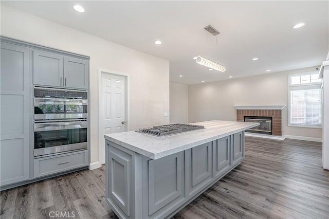 429 Somerset Cir, Corona, CA 92879 - kitchen with appliances with stainless steel finishes, wood finished floors, gray cabinetry, a kitchen island, and hanging light fixtures