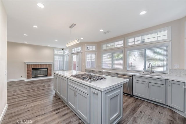 429 Somerset Cir, Corona, CA 92879 - kitchen featuring a sink, appliances with stainless steel finishes, light wood-type flooring, baseboards, and a fireplace