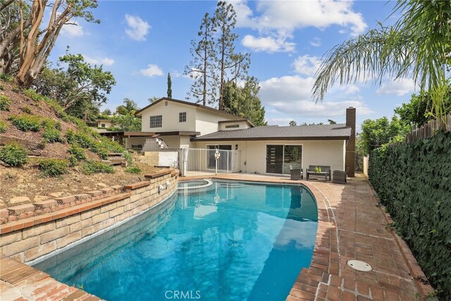 12635 Dorina Pl, Granada Hills, CA 91344 - back of house featuring stucco siding, a chimney, a gate, and a pool with connected hot tub