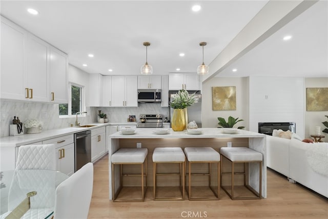 12635 Dorina Pl, Granada Hills, CA 91344 - kitchen with appliances with stainless steel finishes, a sink, a breakfast bar area, backsplash, and white cabinets