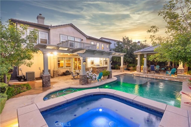 30304 Vercors St, Murrieta, CA 92563 - back of house at dusk with an in-ground hot tub, a patio area, a chimney, and a balcony