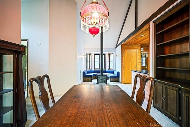 carpeted dining space with a towering ceiling, an inviting chandelier, and built in shelves