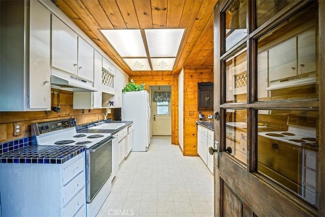 kitchen with a sink, white cabinetry, white appliances, under cabinet range hood, and tile countertops