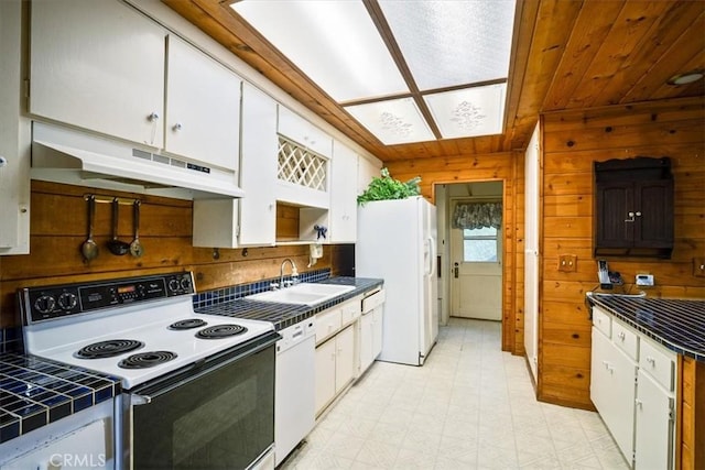 kitchen featuring white cabinets, under cabinet range hood, a sink, and white appliances