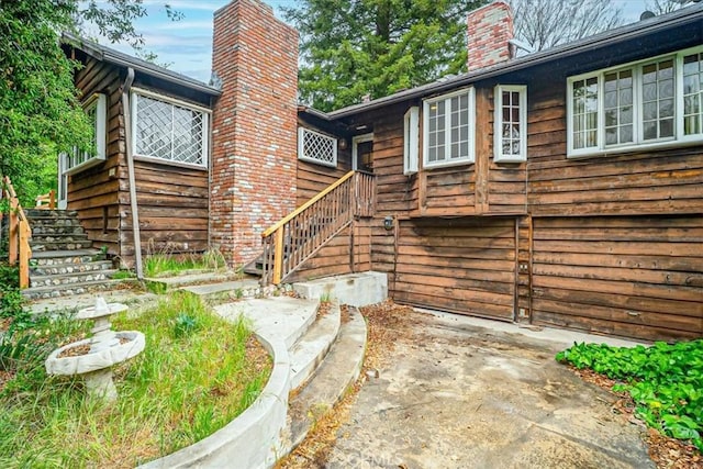 rear view of house featuring stairway and a chimney