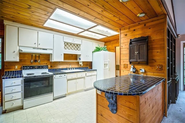 419 Lytle Ln, Lytle Creek, CA 92358 - kitchen with white appliances, tile counters, under cabinet range hood, wood walls, and white cabinets