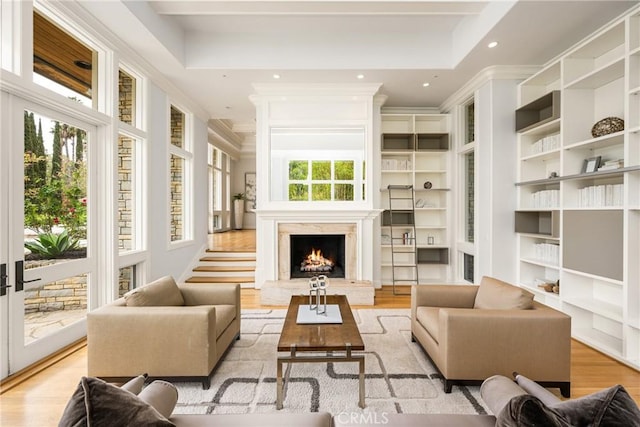 interior space featuring crown molding, a warm lit fireplace, light wood-style floors, built in features, and recessed lighting