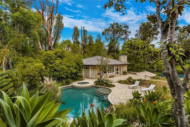 outdoor pool featuring an exterior structure, a patio area, an outbuilding, and an in ground hot tub