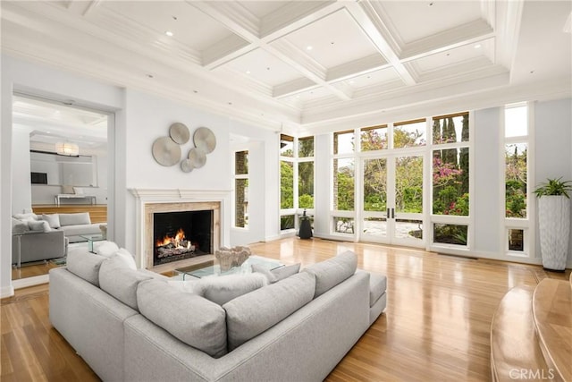 living area with light wood-style flooring, coffered ceiling, beamed ceiling, a high ceiling, and a fireplace