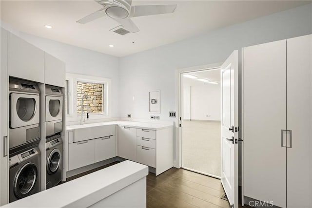 clothes washing area featuring a ceiling fan, a sink, cabinet space, stacked washer and clothes dryer, and visible vents