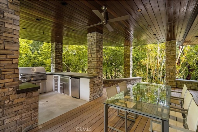 wooden deck featuring grilling area, a ceiling fan, outdoor dining area, and exterior kitchen
