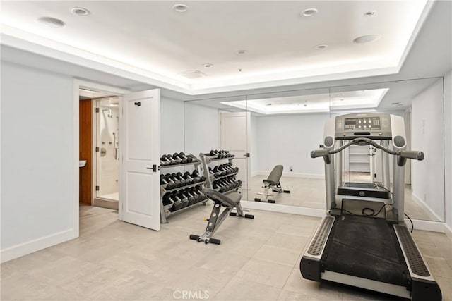 workout area featuring a raised ceiling and baseboards