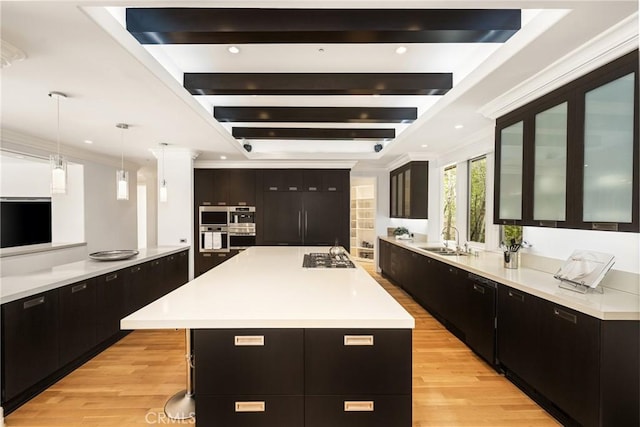 kitchen with dark cabinetry, a sink, light countertops, and light wood-type flooring