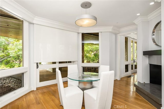 dining space with plenty of natural light, ornamental molding, and wood finished floors
