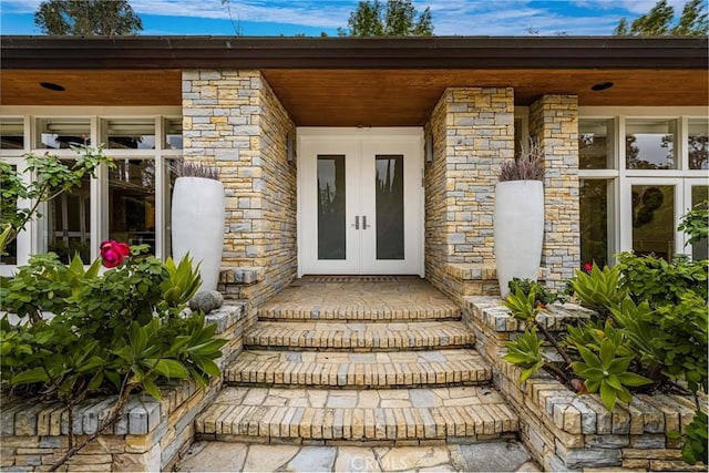 property entrance featuring stone siding, a porch, and french doors
