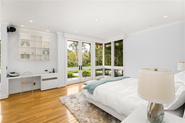 bedroom with crown molding, built in study area, light wood-style floors, french doors, and recessed lighting