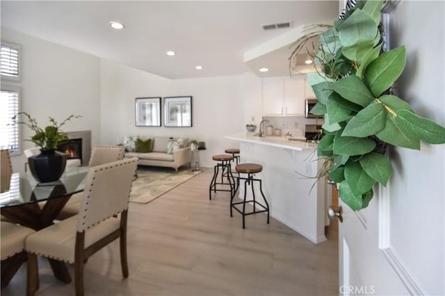 85 Briarglen, Irvine, CA 92614 - dining area featuring light wood-style flooring, recessed lighting, and a warm lit fireplace