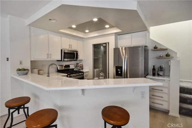 85 Briarglen, Irvine, CA 92614 - kitchen featuring stainless steel appliances, a peninsula, white cabinets, a breakfast bar, and recessed lighting
