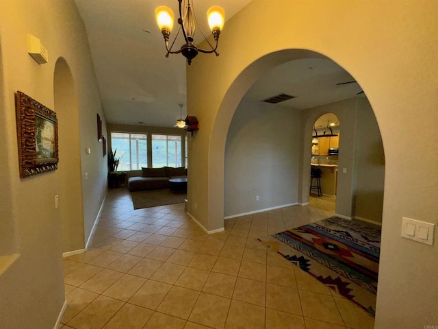 hallway featuring visible vents, a high ceiling, and light tile patterned flooring