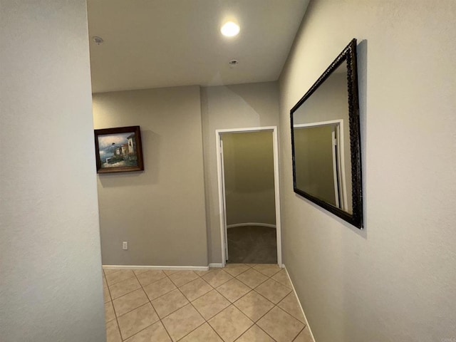 hallway with light tile patterned flooring and baseboards