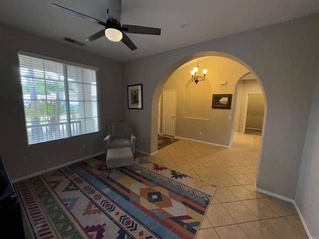 sitting room with visible vents, light tile patterned floors, arched walkways, baseboards, and ceiling fan