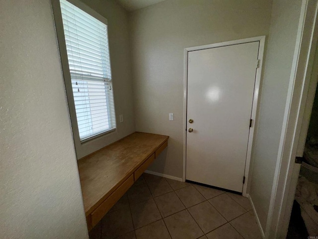 doorway with baseboards and light tile patterned flooring