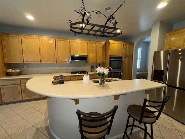 kitchen featuring black cooktop, ventilation hood, stainless steel fridge with ice dispenser, a sink, and arched walkways