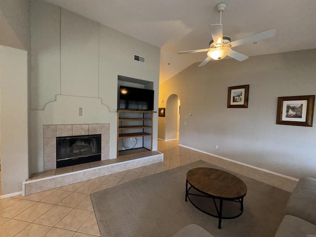 living room featuring tile patterned floors, visible vents, arched walkways, baseboards, and ceiling fan