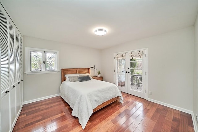 bedroom with baseboards, multiple windows, wood finished floors, and access to exterior