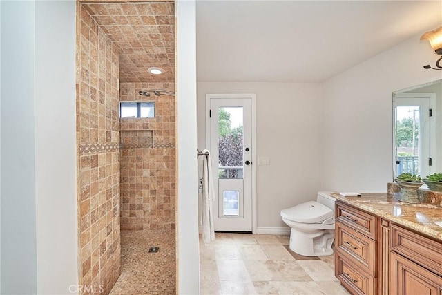full bath with vanity, baseboards, a tile shower, and toilet