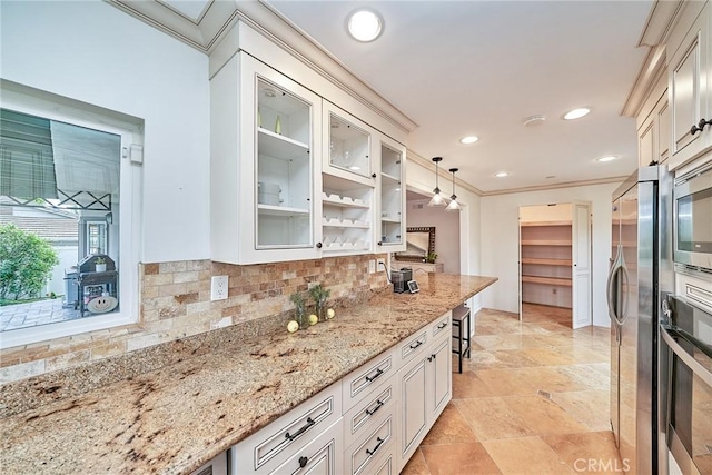 kitchen with light stone countertops, appliances with stainless steel finishes, decorative backsplash, and glass insert cabinets