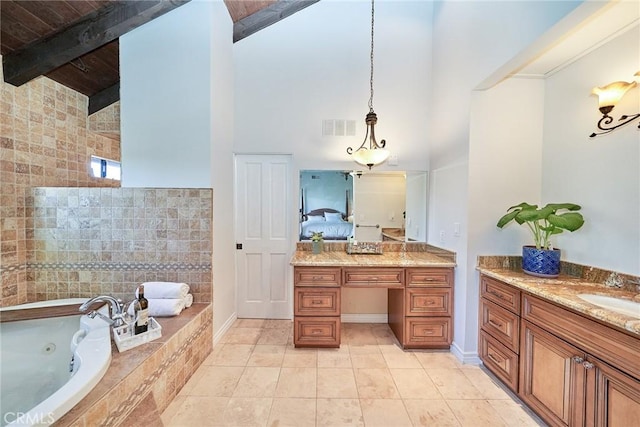 ensuite bathroom featuring visible vents, a tub with jets, beam ceiling, vanity, and connected bathroom