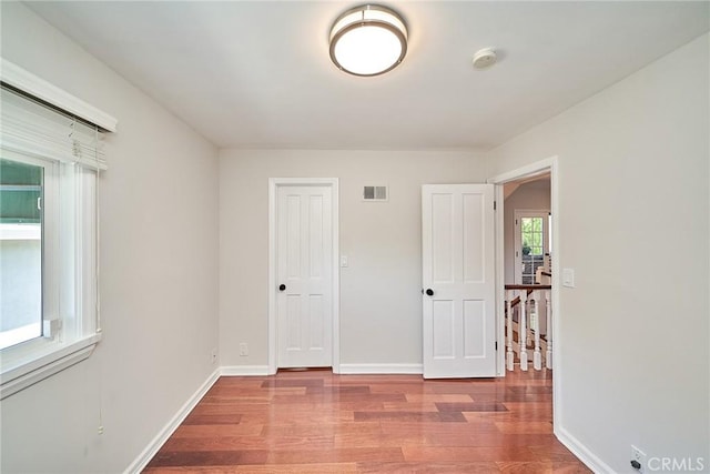 unfurnished bedroom featuring visible vents, baseboards, and wood finished floors
