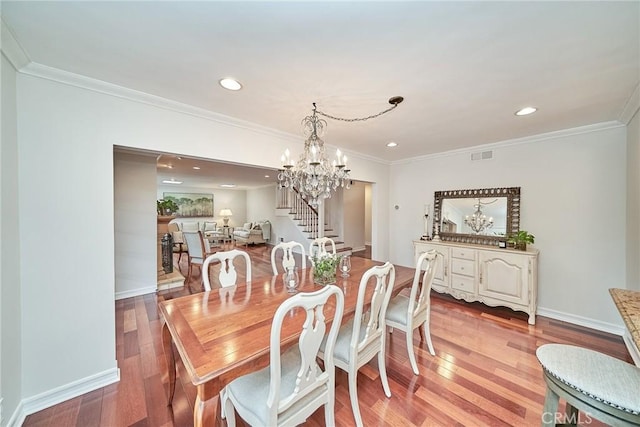dining area featuring light wood finished floors, a chandelier, stairs, baseboards, and visible vents