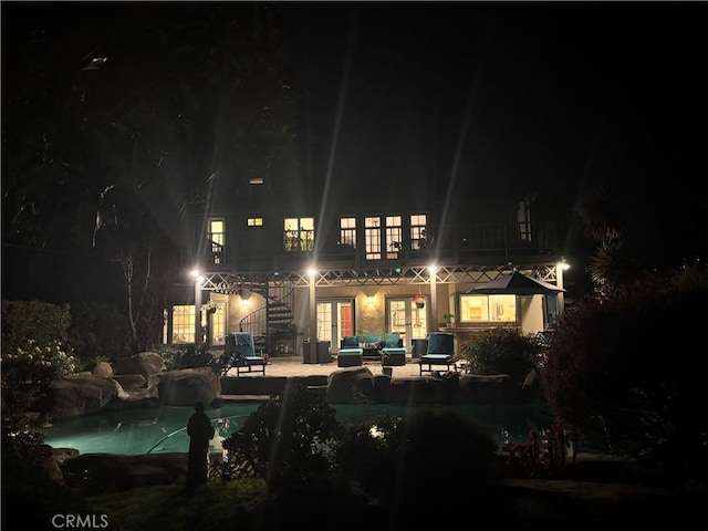 back of house at twilight with a patio, outdoor lounge area, french doors, and an outdoor pool