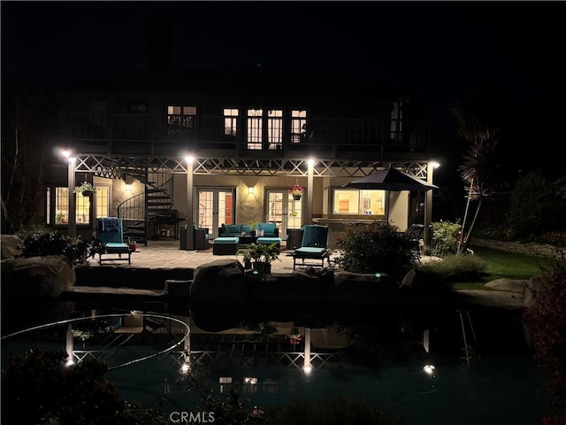 back of house at twilight with french doors, a patio, an outdoor hangout area, and a balcony