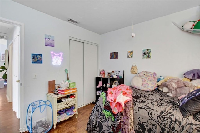 bedroom with wood finished floors, a closet, and visible vents