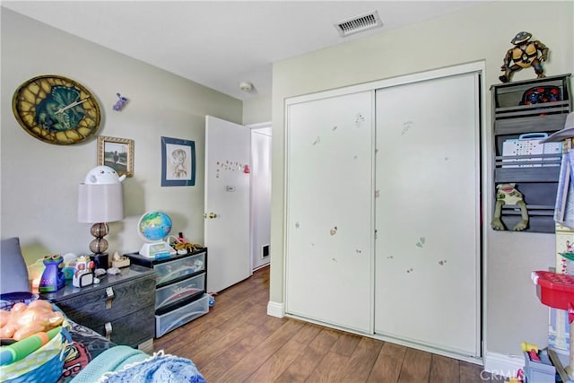 bedroom featuring wood finished floors, visible vents, and a closet