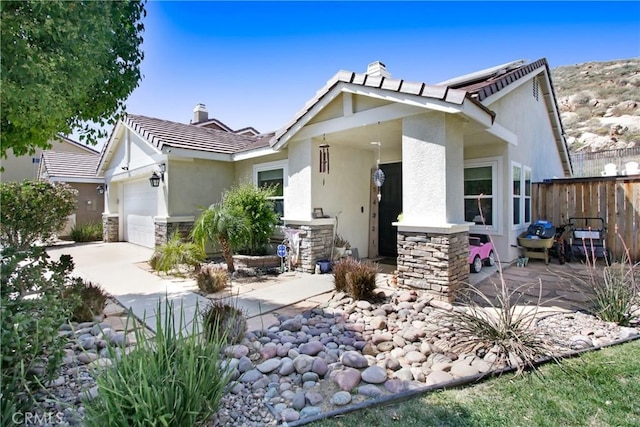 view of front facade featuring a tiled roof, stone siding, fence, an attached garage, and stucco siding