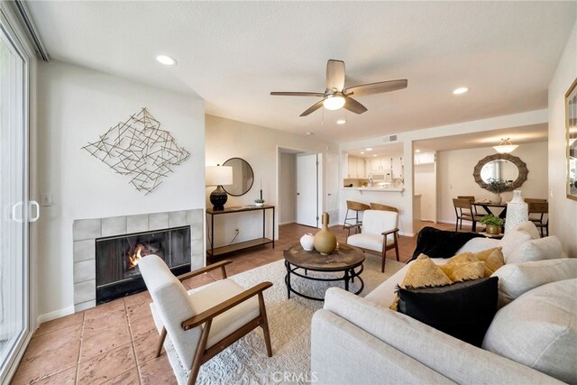 living area with recessed lighting, visible vents, baseboards, a tiled fireplace, and ceiling fan