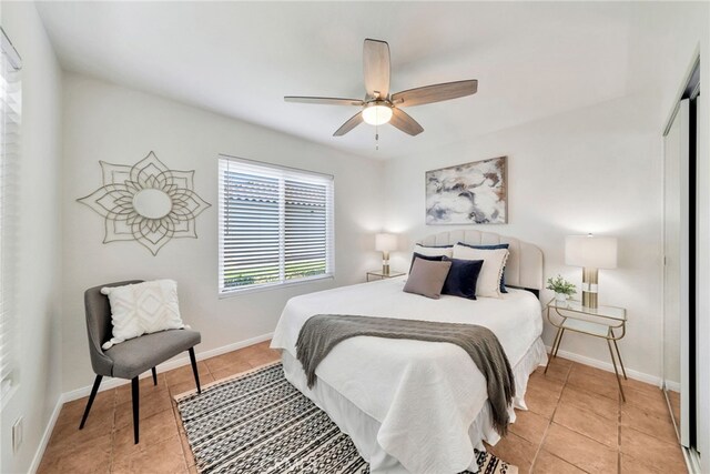 bedroom featuring a closet, baseboards, ceiling fan, and light tile patterned floors