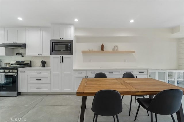 kitchen featuring white cabinets, built in microwave, backsplash, stainless steel gas stove, and under cabinet range hood