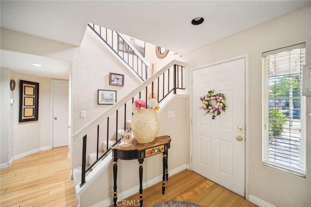 foyer with baseboards, wood finished floors, and stairway