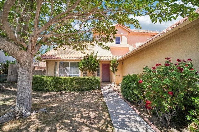 property entrance featuring a tiled roof, stucco siding, and fence