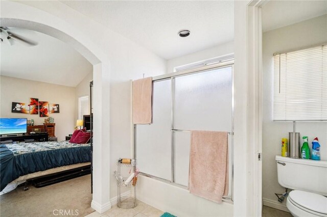 bathroom with combined bath / shower with glass door, toilet, ensuite bath, baseboards, and ceiling fan