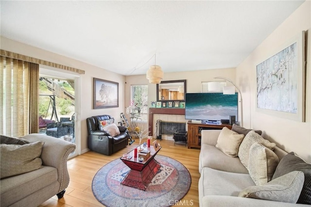 living area featuring light wood-style floors and a tiled fireplace